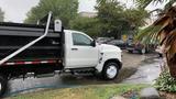 A 2021 International CV515 truck with a black dump bed and white cab parked in a wet area