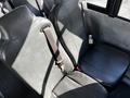 Two black vinyl bus seats with seat belts visible on a blue bus interior