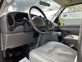 Interior view of a 2004 Ford Econoline showing the driver's seat dashboard and steering wheel with gray upholstery and dashboard controls