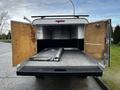 The rear of a 2012 RAM 3500 with large wooden doors open, revealing an empty cargo area featuring a flat surface and a metallic piece inside