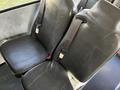 Two black vinyl bus seats with seatbelts, configured for passenger use in a vehicle interior