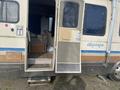 A 1987 Chevrolet Fleetwood Pace Arrow RV with an open door revealing an interior space and steps leading up to the entrance