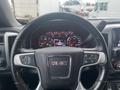 A close-up of a 2015 GMC Sierra 1500 steering wheel displaying various dashboard gauges and controls