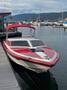 A red and white 1989 Nordic Viking speedboat with a black stripe and a red canopy is docked at a marina