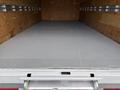 A gray interior of a 2022 Ford E-450 cargo van with smooth flooring and wooden walls