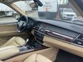 Interior view of a 2009 BMW X5 featuring beige leather seats a wooden trim dashboard and a central control console with audio and climate controls