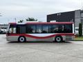 A 2016 Grande West Vicinity bus with red and white coloring featuring large windows and a streamlined body design