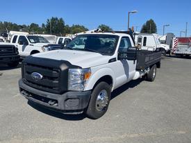 2016 Ford F-350 SD with a flatbed and front grille in the foreground clean white color and chrome accents on the headlights and bumpers