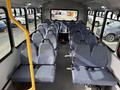 Interior view of a 2018 Chevrolet Express bus featuring rows of blue upholstered seats with safety belts and a metal handrail on one side