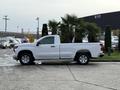 A white 2024 Chevrolet Silverado 1500 pickup truck parked with a large planter of palm trees in the truck bed