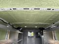 Interior view of a 2023 Ford Transit cargo van showing a green insulated ceiling and silver metal shelving along the sides