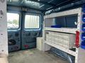 A blue 2010 Ford Econoline van interior featuring a shelving unit and storage boxes with a tool chest along the side walls