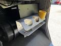 A metallic shelf with three cut-out openings for storage and a yellow cup holder attached to the side inside a vehicle