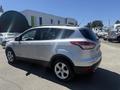 A silver 2014 Ford Escape parked with a streamlined design and five-spoke alloy wheels
