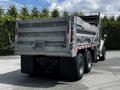 A 2010 Freightliner M2 106 dump truck with a silver metallic bed and dual rear wheels is parked, showcasing its industrial design and heavy-duty build