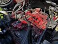 A close-up view of the engine components of a 2012 Freightliner M2 112 showcasing various hoses wires and red painted parts