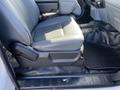A gray leather driver's seat of a 2013 Ford F-250 SD with a black rubber floor mat and a textured floor beneath
