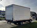 A 2015 Hino 195 box truck with a plain white cargo area and a single rear axel parked in a commercial area