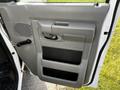 A gray door panel of a 2013 Ford Econoline with a handle and a storage compartment