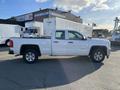 A white 2018 GMC Sierra 1500 pickup truck with a double cab and chrome accents is parked with its side view facing the camera