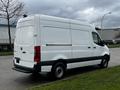 A white 2021 Mercedes-Benz Sprinter van is parked on the side of the road showcasing its sleek design and spacious cargo area