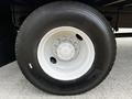 Close-up of a tire mounted on a white wheel featuring several bolts and a smooth surface labeled with the brand name and specifications of the tire