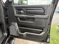 Interior door panel of a 2024 RAM 2500 featuring controls for windows and locks with a textured black finish and integrated storage compartments