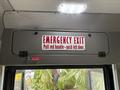 A sign indicating an emergency exit with instructions to pull a red handle and push the left door