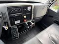 The interior of a 2011 International 4300 featuring a dashboard with controls gauges and a gear shift along with a cup holder and a black leather seat
