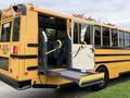 A yellow 2014 Freightliner B2 school bus with an open side door and wheelchair lift accessed from the rear with safety grips on the side