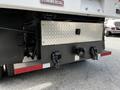 The rear of a 2012 Freightliner M2 106 featuring a metallic diamond plate storage compartment and two towing hooks mounted on a black bumper