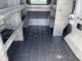 Interior view of a 2013 Ford Transit Connect showing a spacious cargo area with metal shelving along the walls and a rubberized floor surface