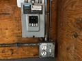 A Siemens electrical panel with circuit breakers and an electrical outlet mounted on a wooden surface