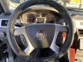 Black leather steering wheel of a 2007 Cadillac Escalade with control buttons and the Cadillac emblem in the center