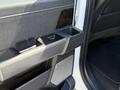 Interior door handle and armrest of a 2024 Ford F-550 Super Duty featuring a fabric finish and controls for windows and a cup holder