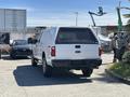 A white 2014 Ford F-250 SD with a truck cap parked with chrome wheels and a visible four-wheel drive badge