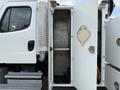 A 2005 Freightliner M2 106 with its doors open revealing a metal compartment and equipment storage area
