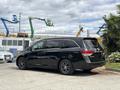 A black 2014 Honda Odyssey minivan parked on a concrete surface with tinted windows and black rims