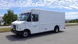 A white 2011 Ford Econoline cargo van with a boxy shape and large front windshield parked on a street