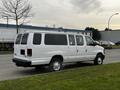 A white 2011 Ford Econoline van parked with multiple side windows and a spacious rear section