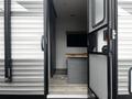 A 2022 Aspen Trail travel trailer with an open door revealing a modern interior featuring a wood countertop and a dark window shade