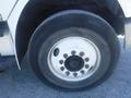 A close-up of a 2005 Freightliner M2 106 Medium Duty truck tire showing a white rim with multiple bolts and a partially deflated tire