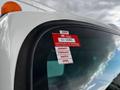 A 2022 Isuzu NPR with a certificate of approval sticker on the driver's side window displaying the months January to April