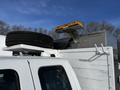 A 2011 Ford F-450 SD with a mounted flashing amber light on the roof and a spare tire placed on top of the vehicle