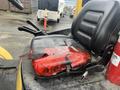 A black seat on a yellow Hyster forklift with a red package taped on top of it