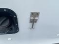 A silver latch attached to a light blue surface next to a circular fuel cap opening