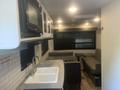 Interior of a 2022 Keystone Hide Out RDWE 20RDWE featuring a kitchenette with a sink and microwave and a seating area with a sofa and table