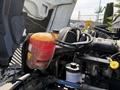 Engine compartment of a 2011 International 4300 featuring a coolant reservoir with orange fluid and hoses connected to the engine components