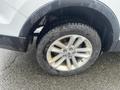 A close-up of a tire and alloy rim from a 2016 Ford Explorer with visible treads and rain droplets on the surface