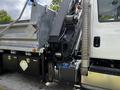 A 2017 International WorkStar 7600 truck with a hydraulic lift mechanism and a silver dump body featuring black storage compartments on the side